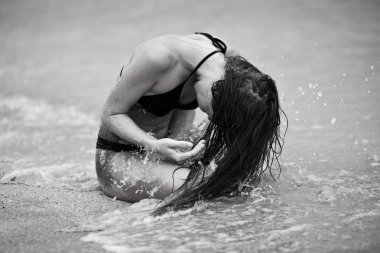 kum plajı üzerinde oturan kadın