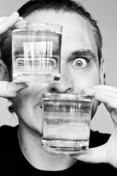 Reflexion eines männlichen Gesichts in Gläsern mit Flüssigkeit — Stockfoto