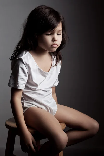 Ledsen flicka sitter på stol — Stockfoto