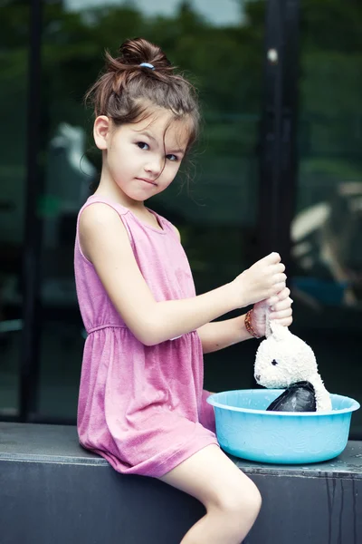 Маленькая девочка моет свою игрушку — стоковое фото