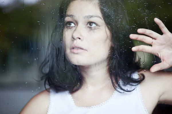 Mulher triste olhando através da janela — Fotografia de Stock