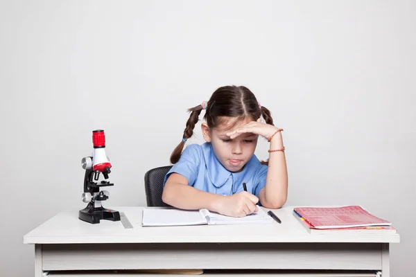 Školačka studovat s mikroskopem — Stock fotografie