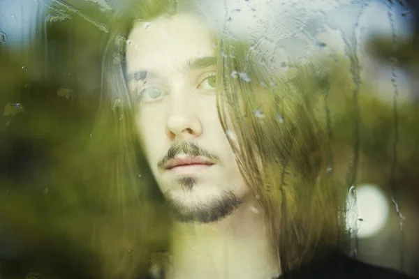 Typ mit langen Haaren vor dem Fenster — Stockfoto