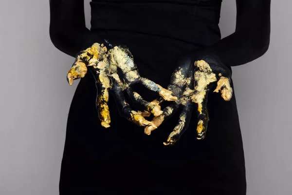 Женщина показывает руки с золотой краской — стоковое фото
