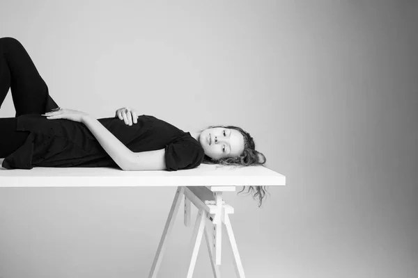 Mulher descansando em uma mesa em um estúdio de fotos — Fotografia de Stock