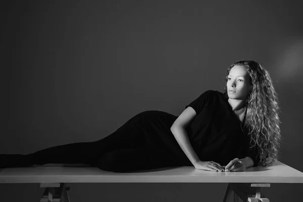 Femme reposant sur une table dans un studio photo — Photo