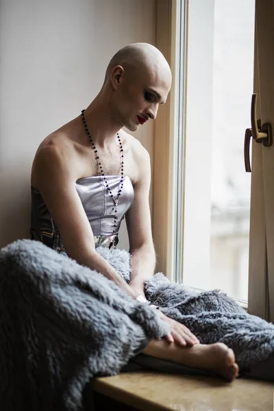 Handsome bald man in a dress sitting by the window