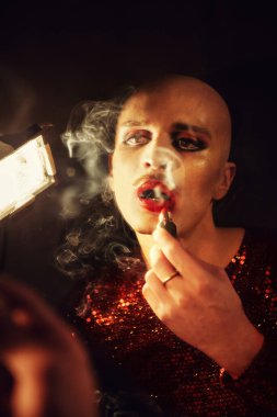 Adam aynanın önünde kendine makyaj yapıyor.