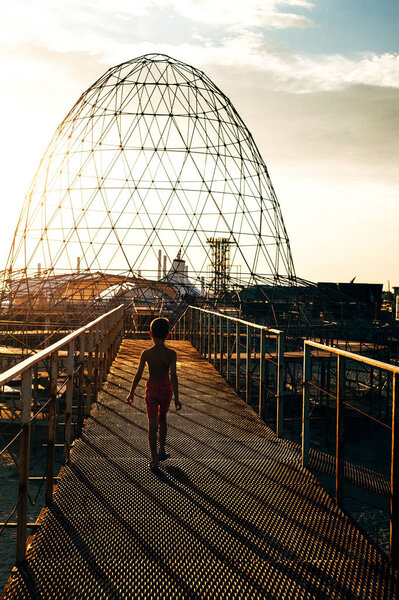  boy walking along metal bridge