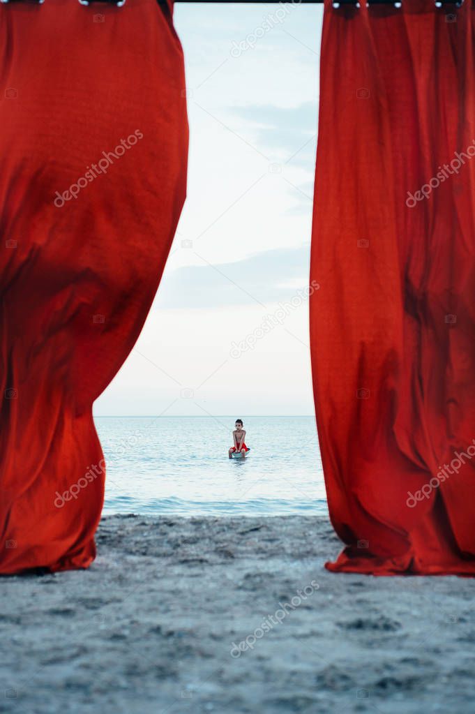 Red curtains and boy in sea 