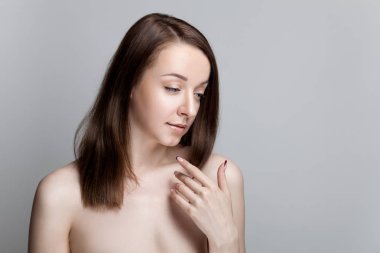 Gri bir arka plan üzerinde çıplak omuz olan esmer kadın