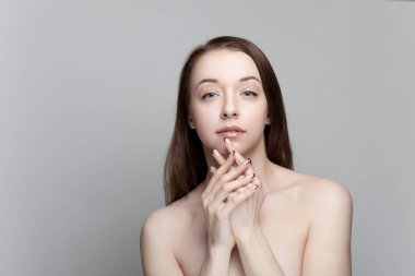 Gri bir arka plan üzerinde çıplak omuz olan esmer kadın