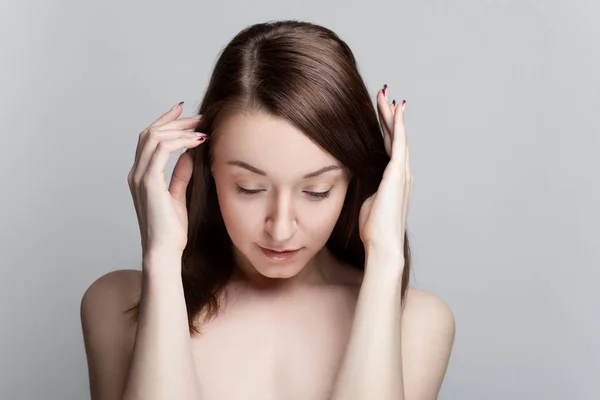 Jonge brunette vrouw met blote schouders op een grijze achtergrond Stockafbeelding