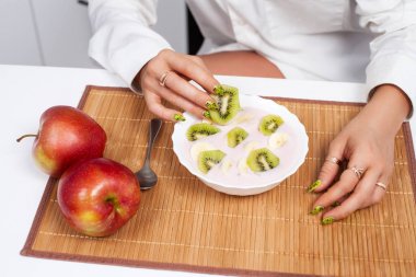 Bir kız bir parça kivi elinde tutuyor.