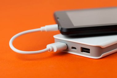 Tablet bilgisayar üzerinden harici pil, turuncu bir arka plan üzerinde kullanılıyorsa.