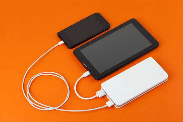 Een smartphone en een tablet-pc worden tegelijkertijd vanaf een externe batterij aangerekend. Rechtenvrije Stockafbeeldingen