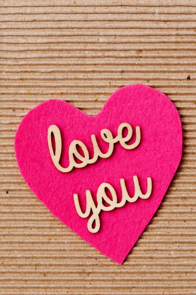 Love You - houten woorden op roze hart met gegolfd papier achtergrond — Stockfoto