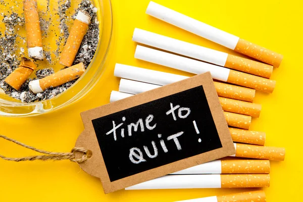 Proibido fumar - Tempo para encerrar - com cigarros, cinzeiro e quadro preto escrito à mão no fundo amarelo — Fotografia de Stock