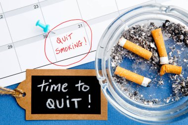 Kül tablası ve el yazısı yazı tahtası üzerinde mavi arka plan ile yasaktır - Takvim - zaman çıkın - çıkın