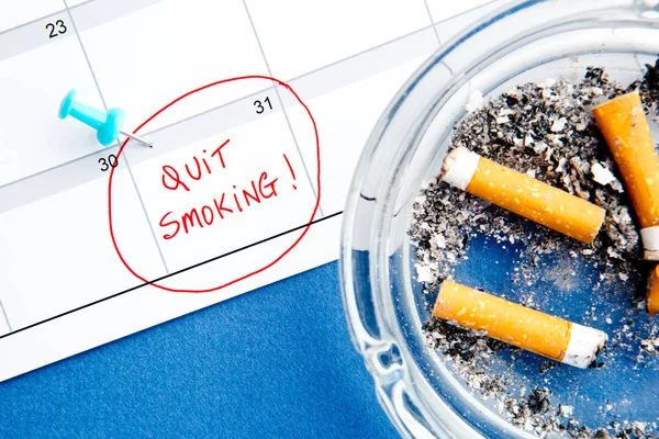 Parar de fumar data do calendário - com cinzeiro no fundo azul — Fotografia de Stock