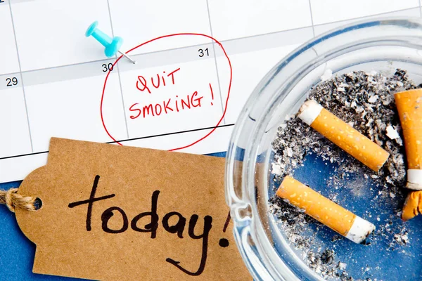 Parar de fumar - Calendário - Hoje - com cinzeiro e etiqueta manuscrita no fundo azul — Fotografia de Stock