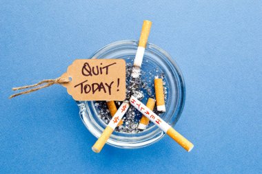 Sigara, kül tablası ve mavi arka plan üzerinde el yazısı etiketi ile - bugün istifa - sigara durdurmak
