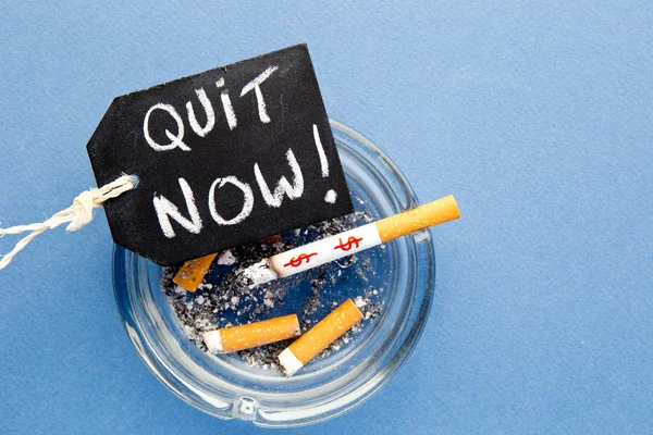 Pare de fumar - Sair agora - com cigarros, cinzeiro e quadro-negro em fundo azul — Fotografia de Stock