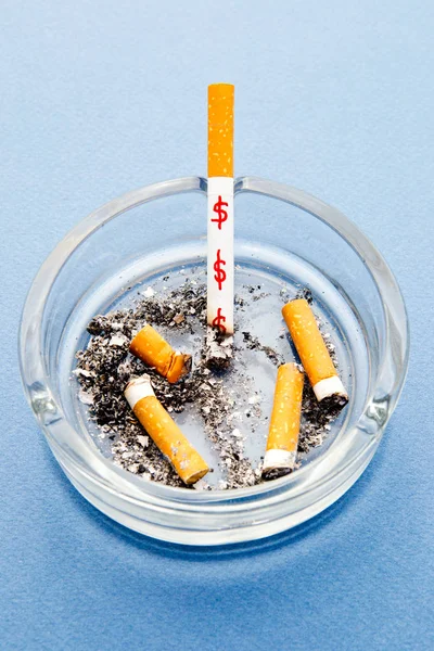 Stop Smoking - waste of money / dollars - with cigarettes and ashtray on blue background