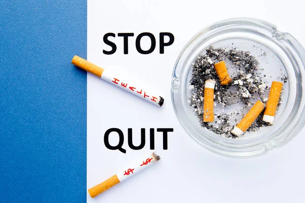 Parar de fumar - Parar e parar - com cigarros e cinzeiro com palavras impressas em fundo azul e branco — Fotografia de Stock