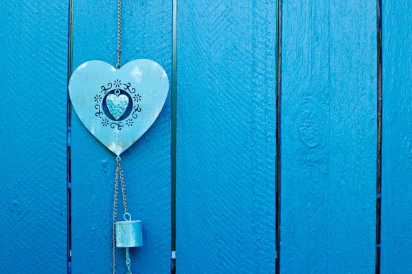 Background - Decorative blue metal heart hanging on blue wooden fence