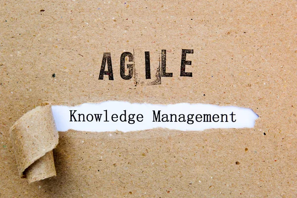 Agile Knowledge Management - printed text underneath torn brown paper with Agile printed in ink