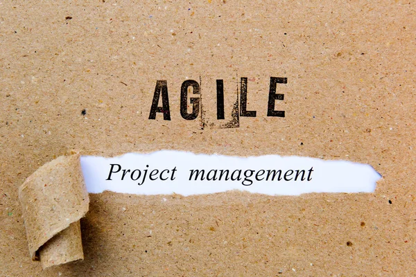 Agile Project Management - printed text underneath torn brown paper with Agile printed in ink