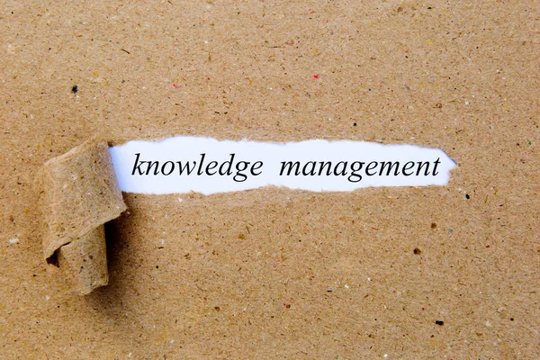 Knowledge Management - printed text underneath torn brown paper