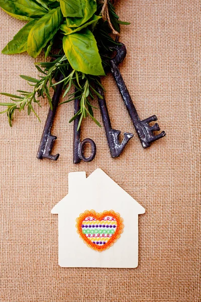 Liefde sleutels met huis en kruiden op jute achtergrond — Stockfoto