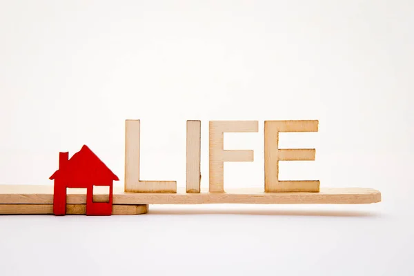 Červená ikona domů s životem v dřevěné písmena na bílém pozadí — Stock fotografie