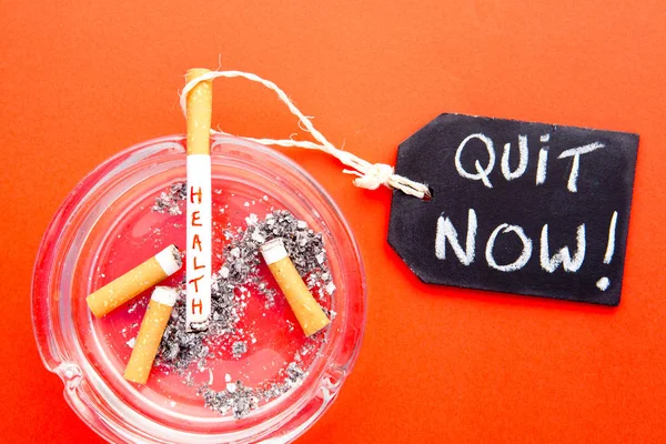 Sair agora - Parar de fumar - Saúde - com cigarros, cinzeiro e quadro-negro no fundo vermelho — Fotografia de Stock