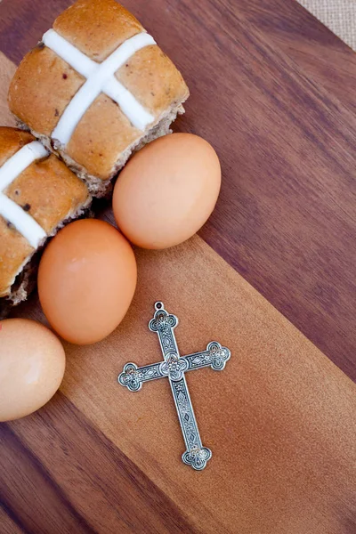 Easter - crucifix, hot cross buns and eggs on wooden cutting board