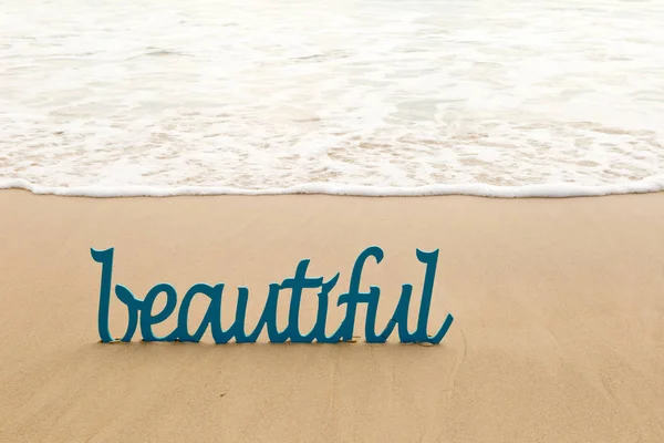 Красиве - синьо-дерев'яне слово в піску з хвилями на пляжі — стокове фото