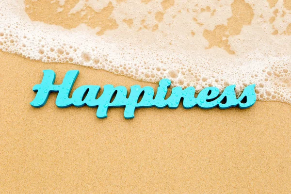 Happiness - blue wooden word on sand with wave — Stock Photo, Image