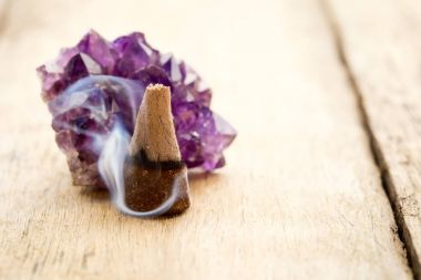 Burning incense cone with amethyst crystal with wafting smoke on clipart