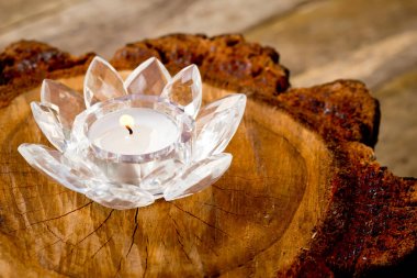 Candle burning in crystal lotus flower holder sitting on cross s clipart