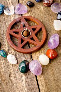 Incense burning in wooden pentagram burner with crystals in hear clipart