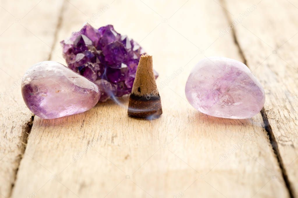 Burning incense cone with amethyst crystals with wafting smoke o