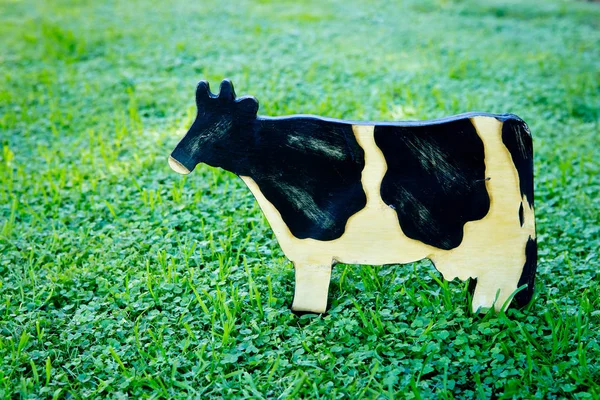 Ahşap boyalı siyah beyaz süt ineği çimenlerin üzerinde — Stok fotoğraf