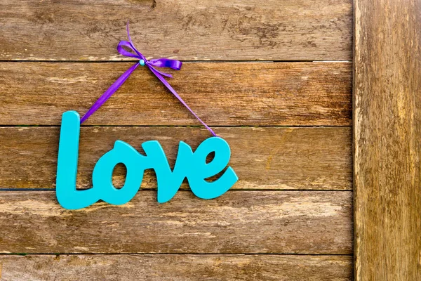 Liefde - blauwe turkoois geschilderde houten woord over paarse lint hangi — Stockfoto