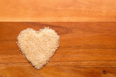 Aşk ham şeker - ahşap arka plan üzerinde kalp şeklinde ham şeker