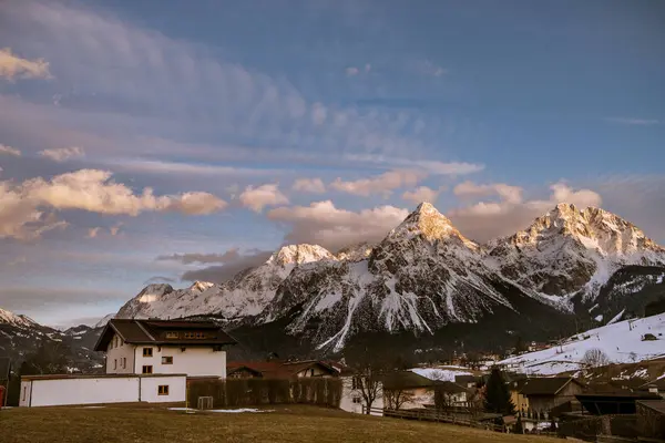 Aldeia abaixo de picos de montanha cobertos de neve — Fotografia de Stock