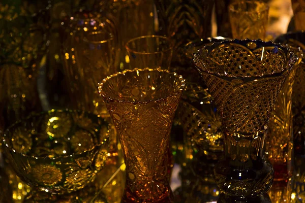 A gold glass vase on a background of blurred vases. Gold glass background.