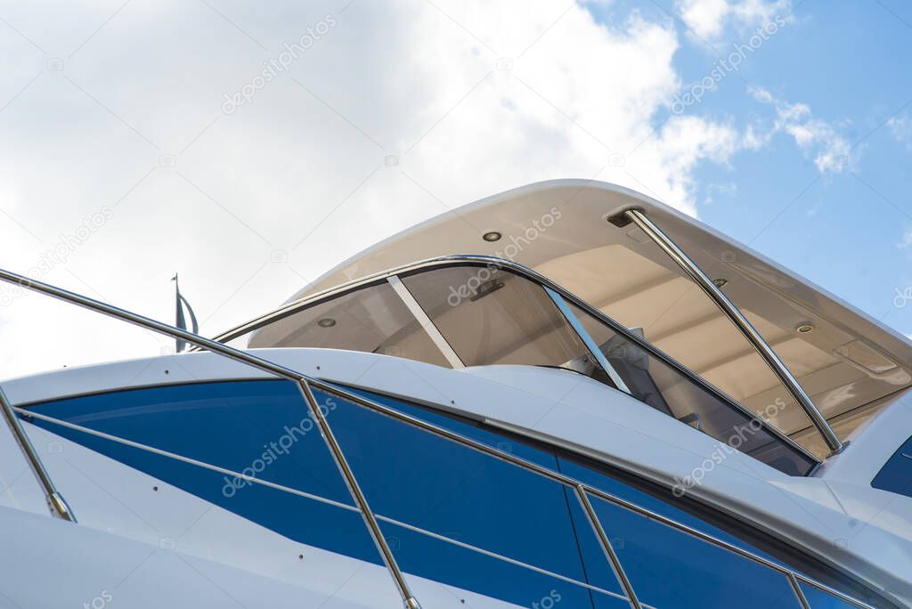 Nautical background of a row of luxury yachts, with black tinted windows and chrome metal railings on white fiber glass bows