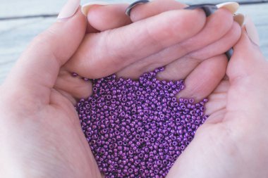 Bir kızın elinde mor tohum boncuk